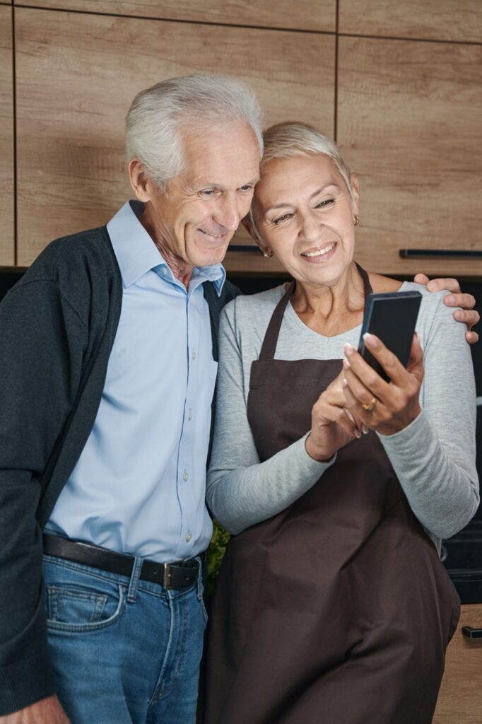 Groß (portrait-of-happy-man-embracing-his-wife-2024-10-22-00-22-28-utc) Ehepaar sucht Reise am Handy heraus.